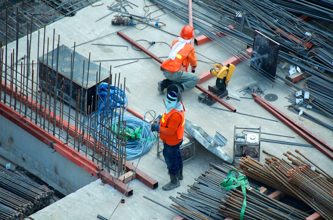 Construction workers on a site with exposed steel beams, representing scope and delivery risk on a government contract