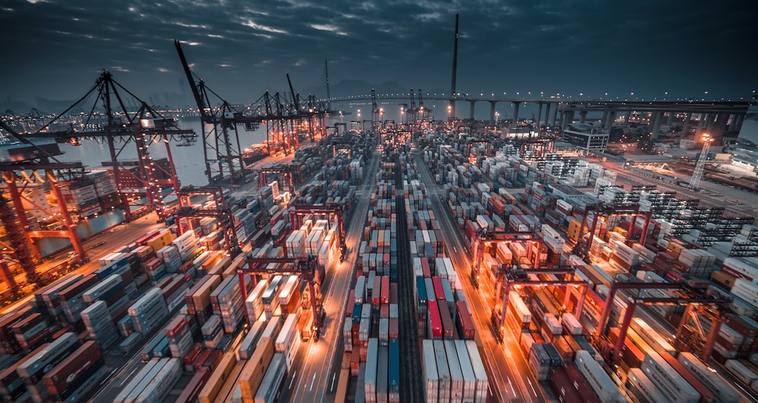 Stacked shipping containers at a port, representing supply chain and tariff risk for a Canadian bidder