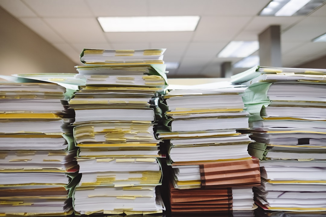 Stacks of paper documents and file folders on an office desk