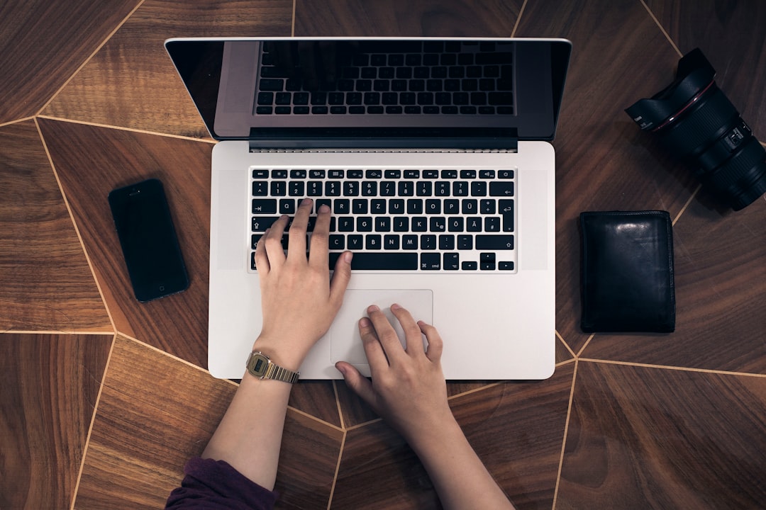 Close-up of hands typing on a laptop keyboard, filling out an online form