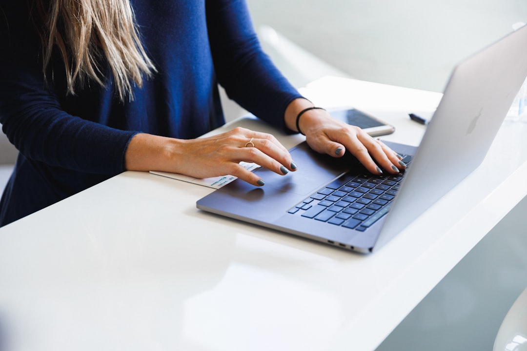 Close-up of hands typing on a laptop keyboard in an office setting