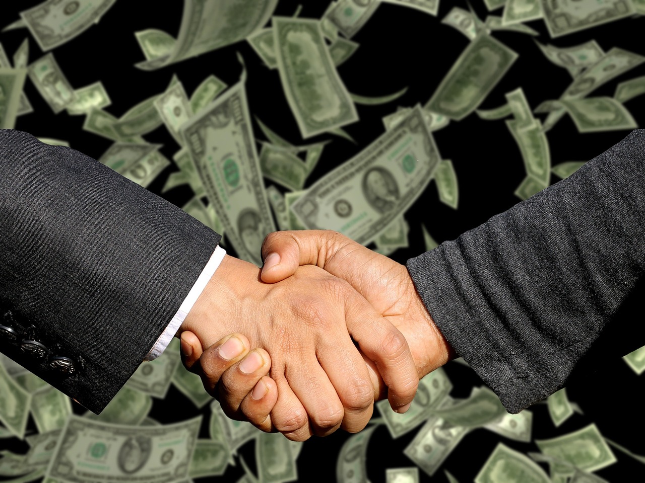 Two business people shaking hands over a signed agreement