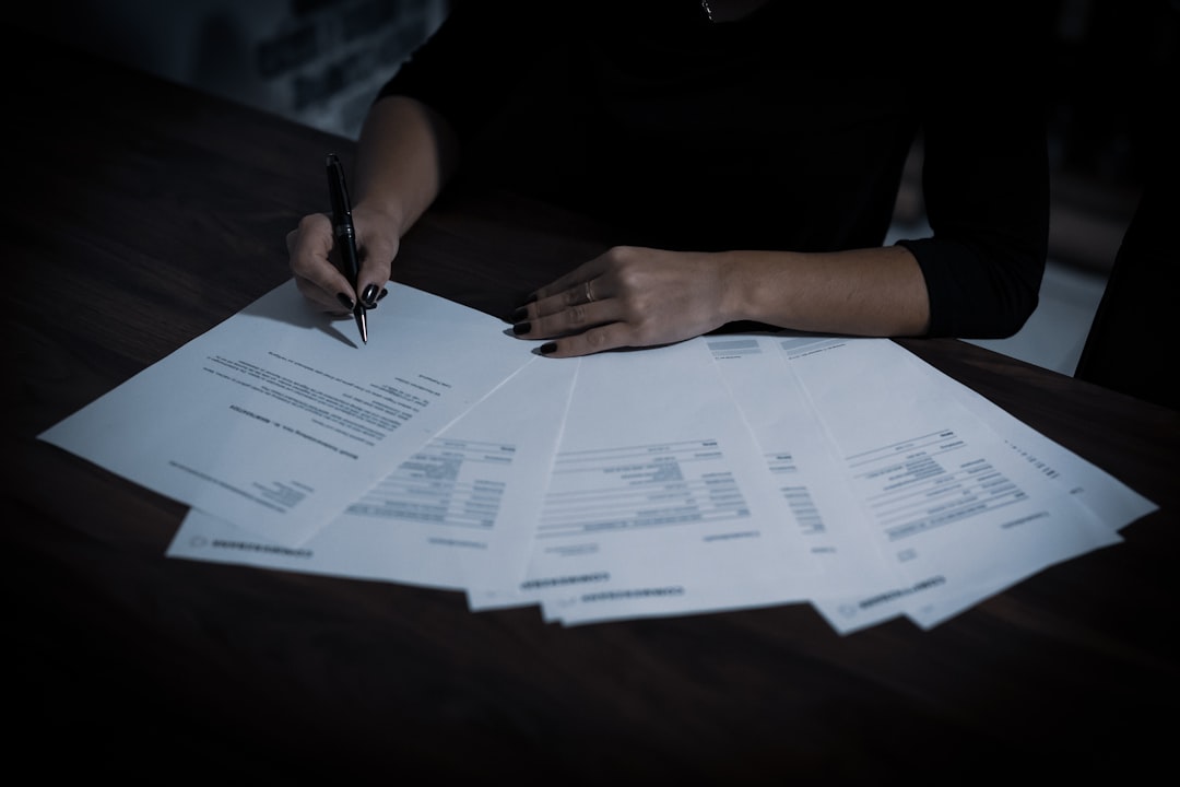 A small business owner reviewing a document and writing notes at an office desk