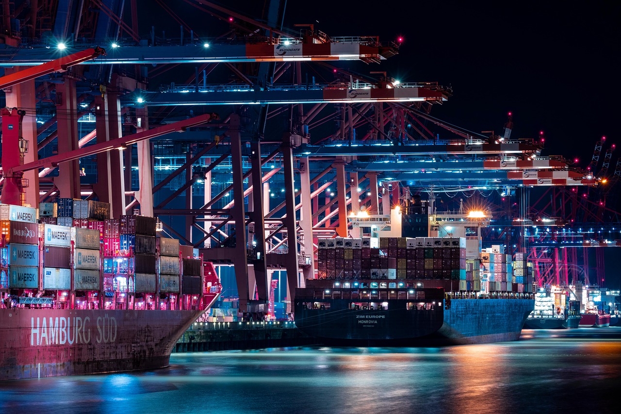 Shipping containers stacked at a busy port with a crane in the background