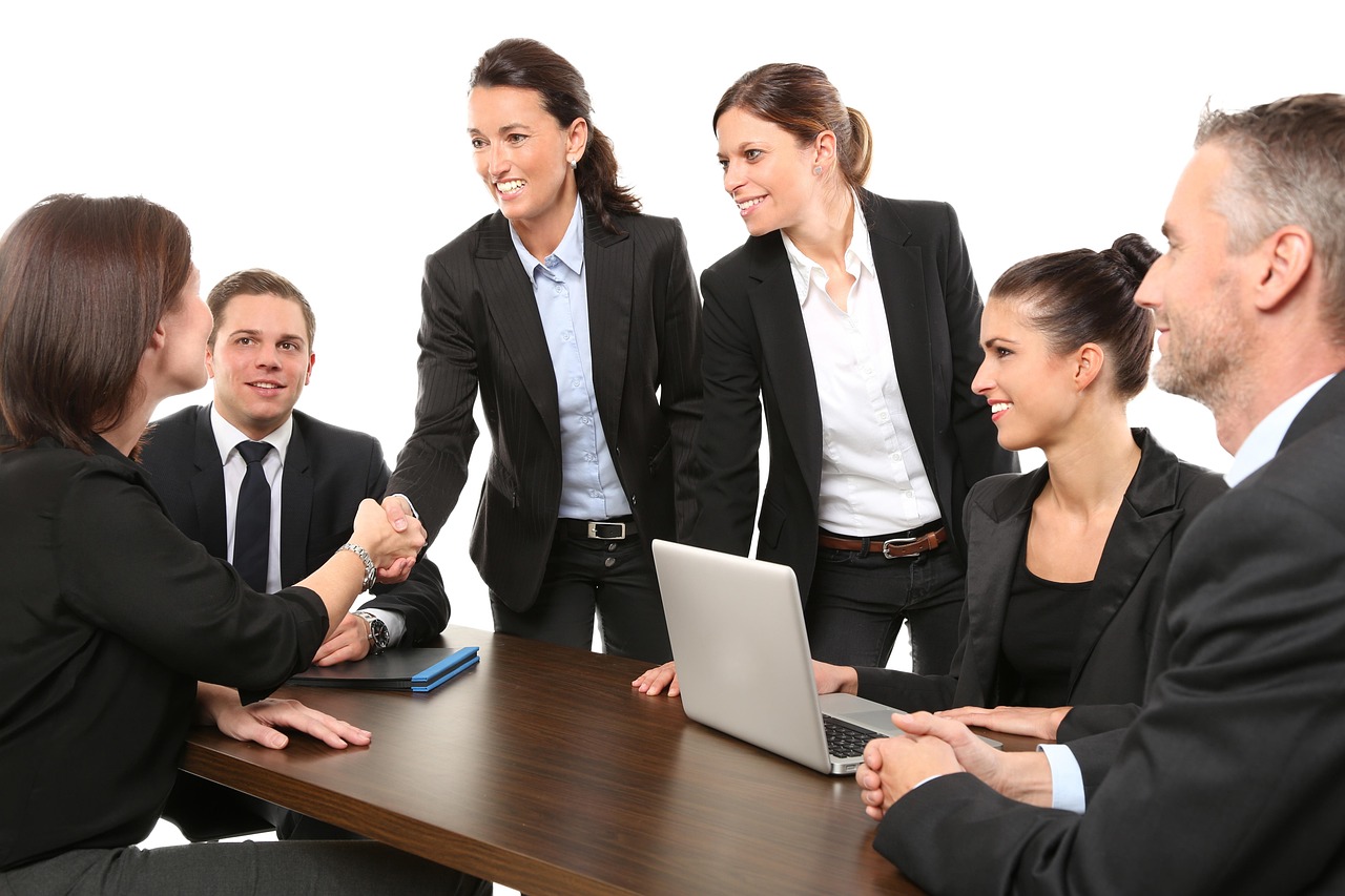 A small group of colleagues in a meeting room discussing documents together, weighing a business partnership