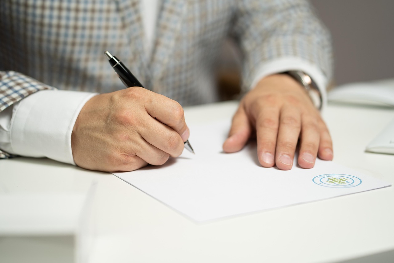 Person signing a contract document with a pen