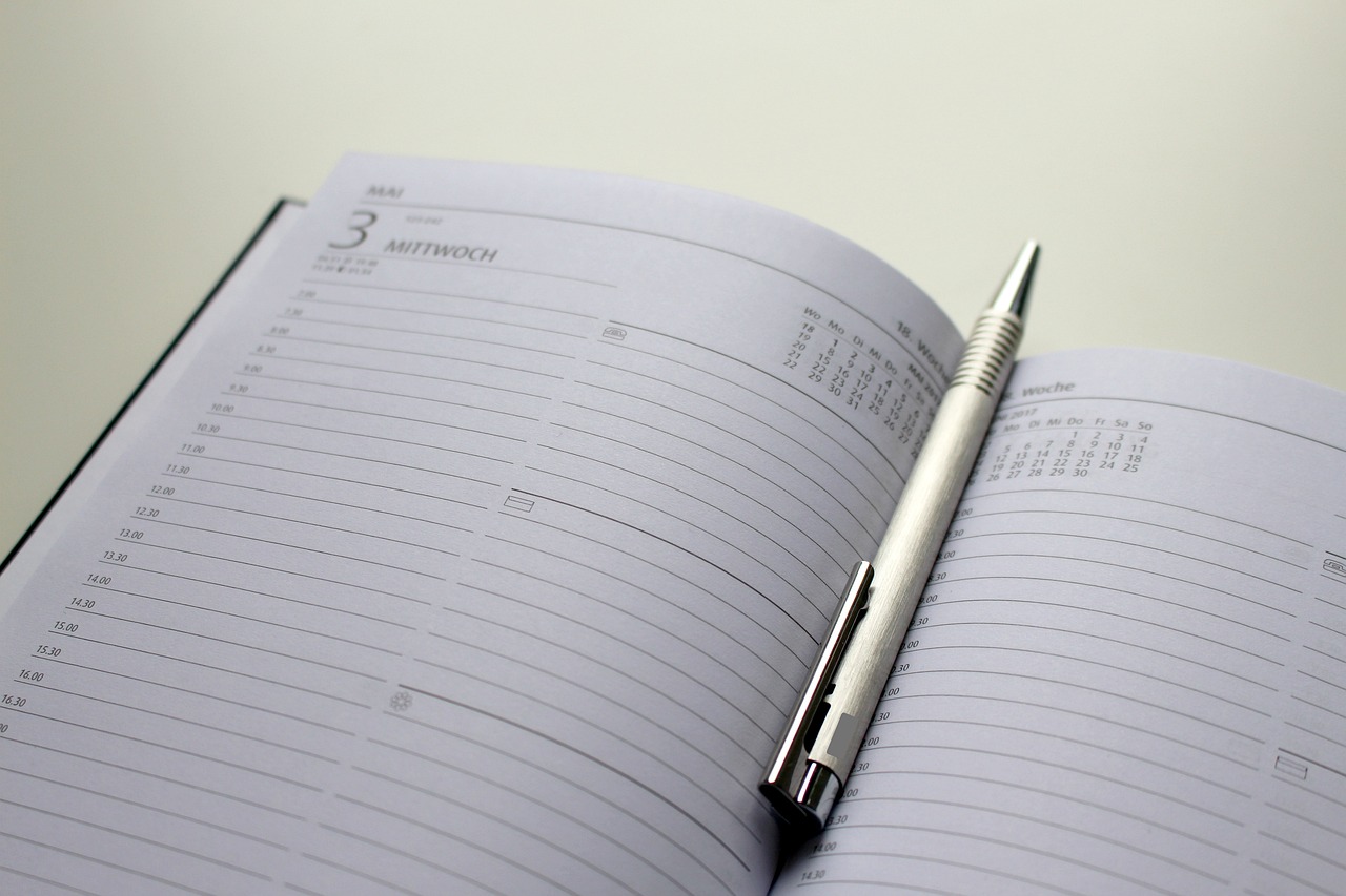A desk calendar and notebook used for planning deadlines, evoking fiscal year-end scheduling
