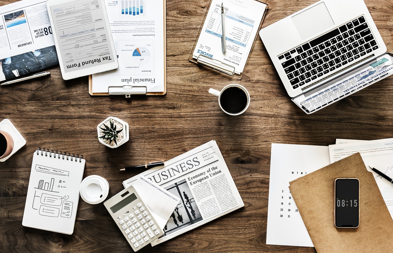 Small business owner working on a laptop at a desk covered in documents and paperwork