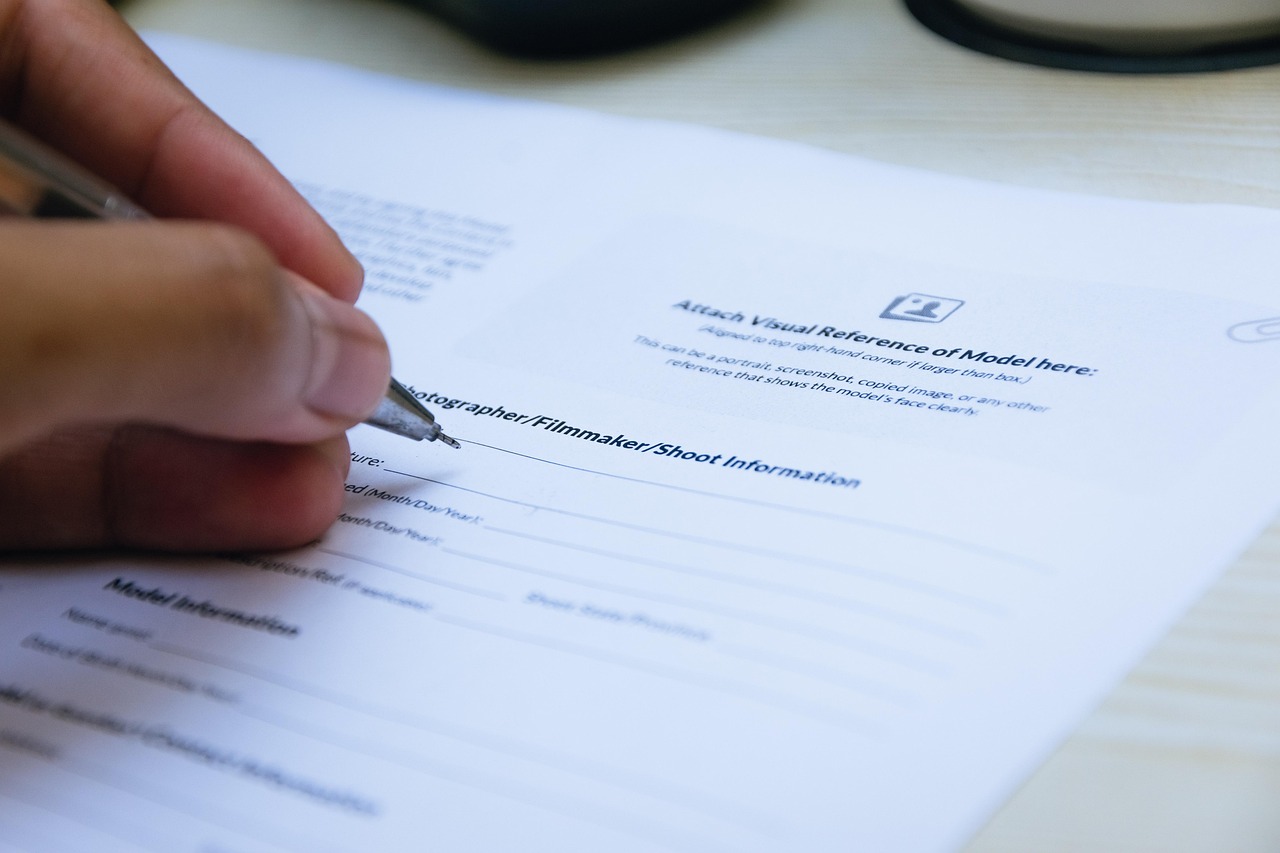 Close-up of a hand signing a business document with a pen on a desk