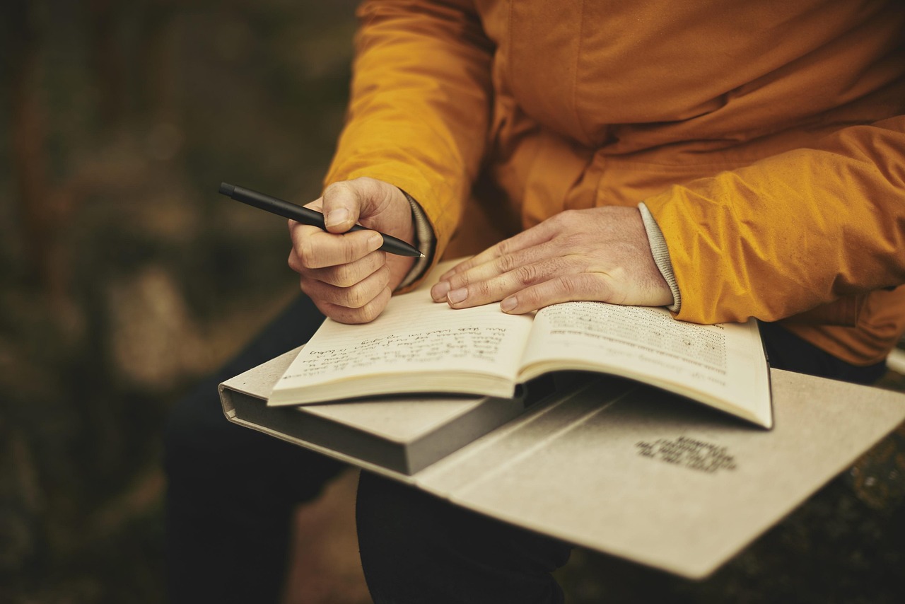 A man signing and reviewing a document up close by hand, checking details before submission