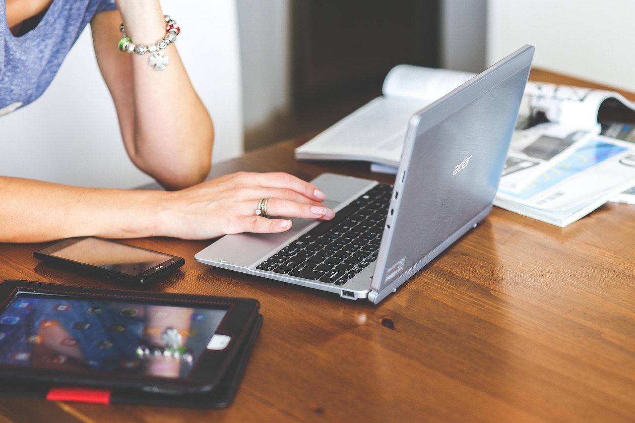 Hands typing on a laptop keyboard while working through business documents at a desk