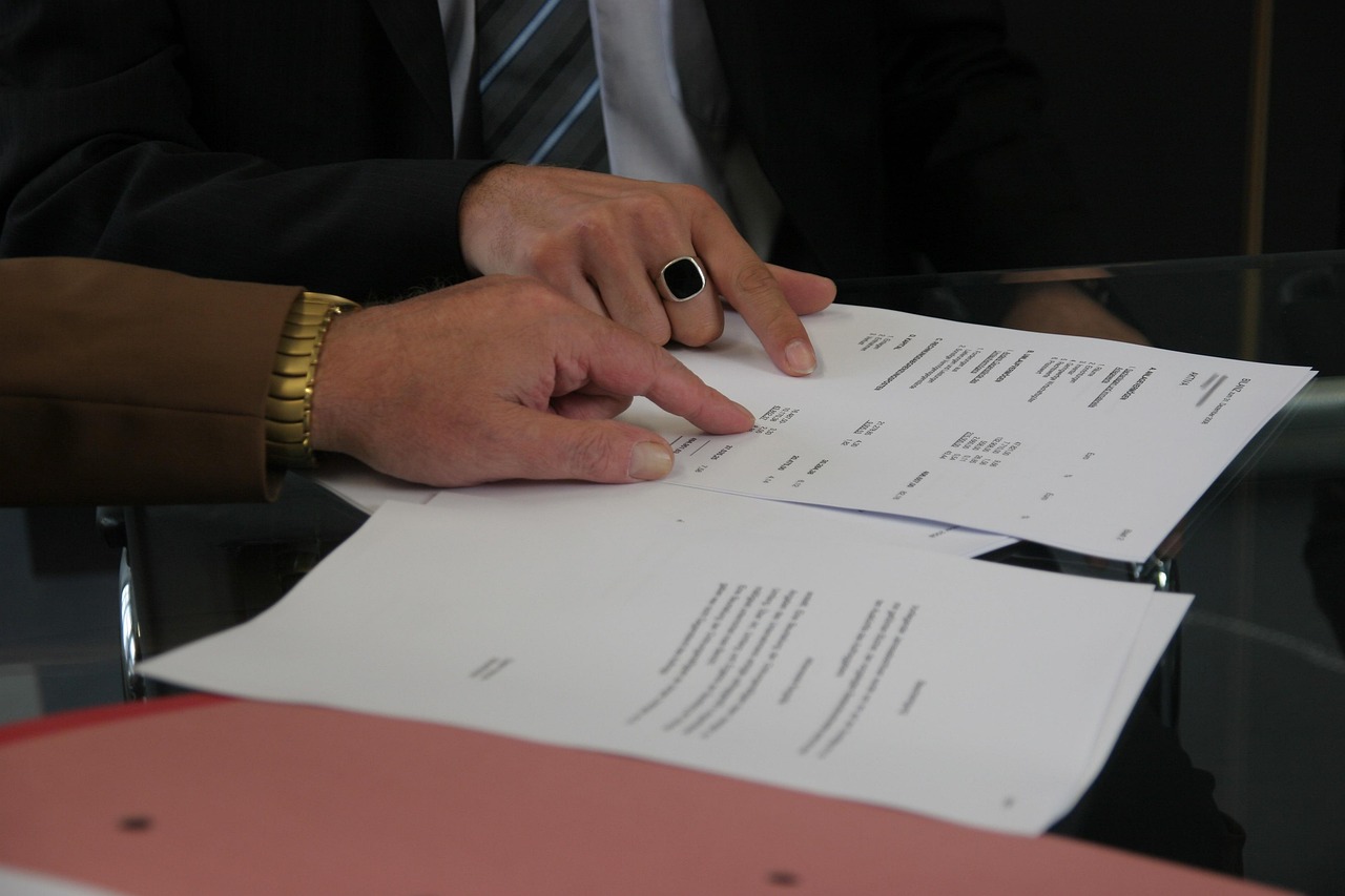 A hand signing a printed contract document at a desk